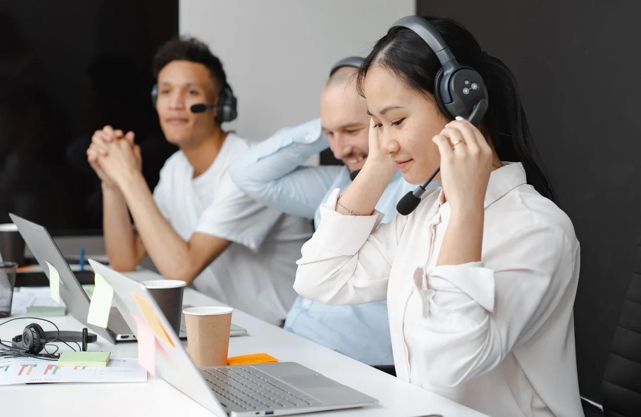 Un equipo comercial con diademas atendiendo llamadas desde sus laptops